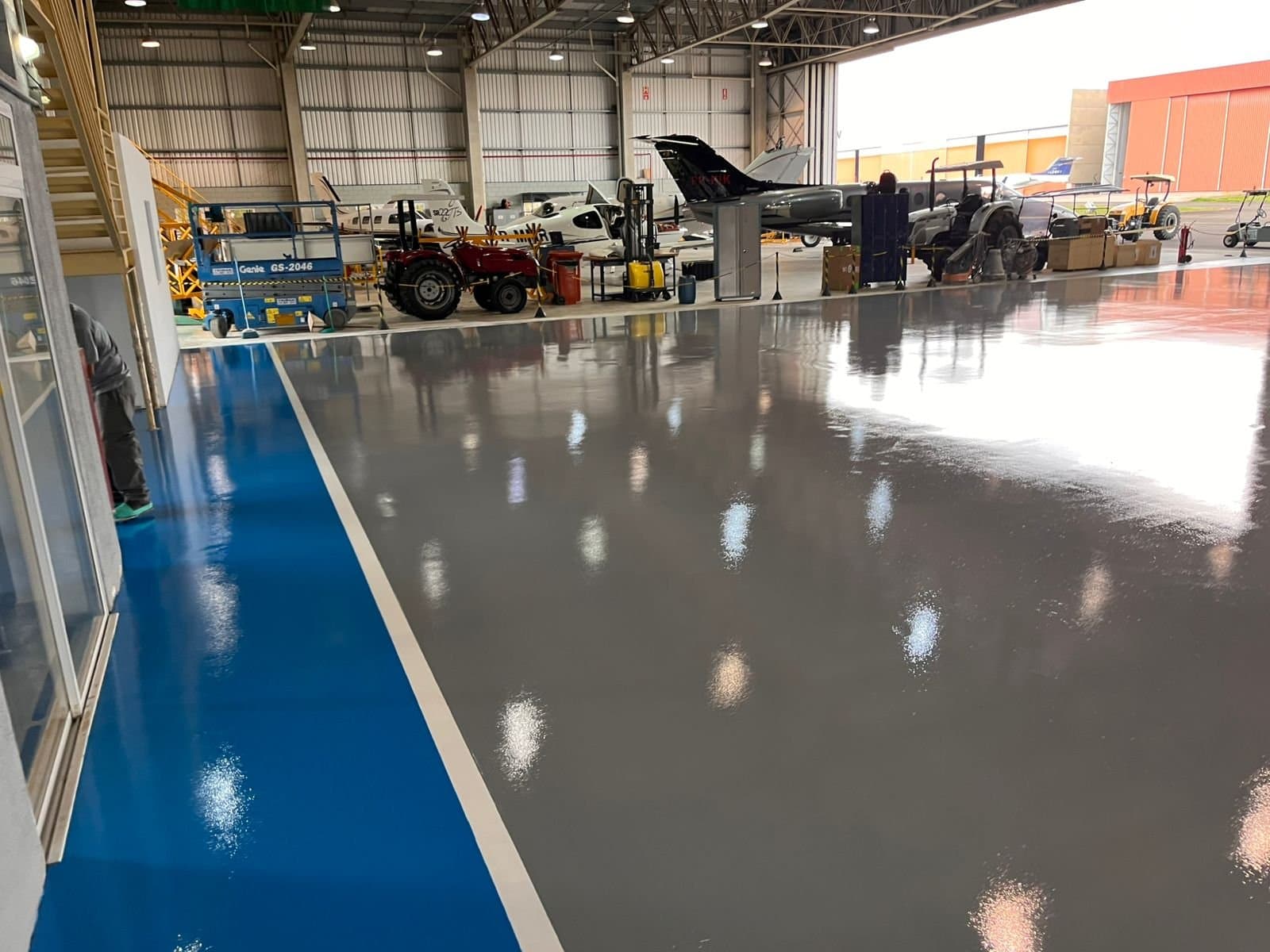 Interior de hangar com piso claro de alto brilho refletindo a aeronave